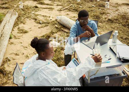 Black Ecologists Analyzing Environmental Samples with Laptop Outdoors Stock Photo