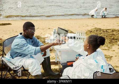 Black Ecologists Analyzing Water Samples during Field Research Stock Photo