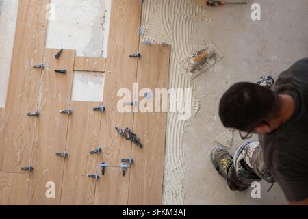 Worker laying down new ceramic tiles with adhesive and leveling system Stock Photo
