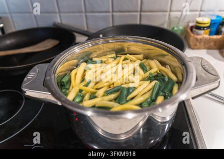 Yellow and green beans cooking in stainless steel pot on kitchen stovetop during meal preparation Stock Photo