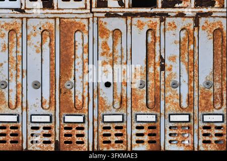 Horizontal detailed photograph of old vintage metal mailboxes covered with heavy rust and corrosion spots. Stock Photo