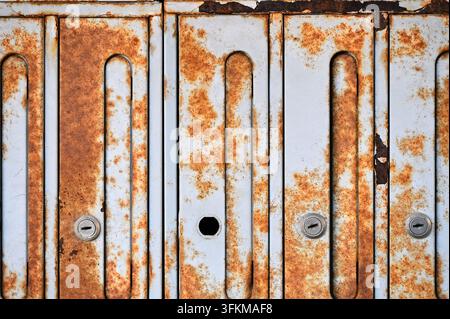 Horizontal detailed photograph of old vintage metal mailboxes covered with heavy rust and corrosion spots. Stock Photo