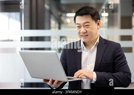 Businessman using a laptop for financial analysis and corporate communication in a modern office. Professional man working on a project with focus and productivity while reviewing digital data. Stock Photo