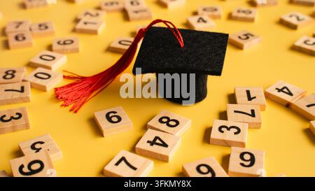 Graduation Cap Toy on Scattered Wooden Number Blocks for Education Concept Stock Photo
