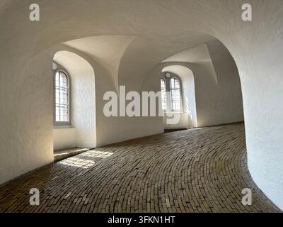 Spiral ramp inside the Round Tower (Rundetaarn) with a curved brick floor, white walls and arched windows, Copenhagen, Denmark Stock Photo