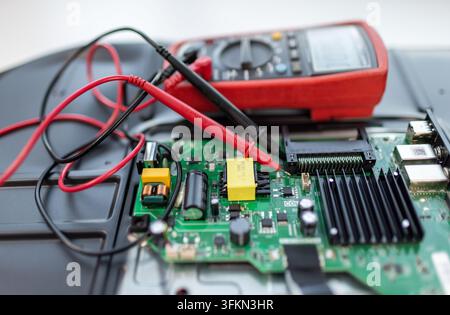 Red multimeter probes test green circuit board components Stock Photo