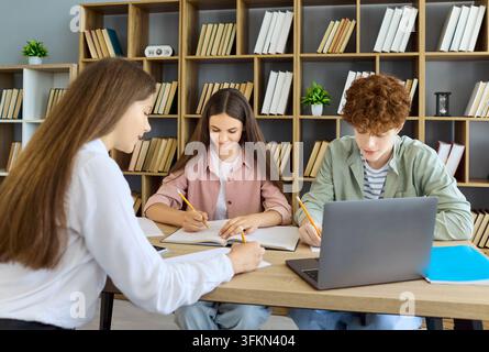 Students collaborating on laptop homework in modern library, teamwork and learning Stock Photo