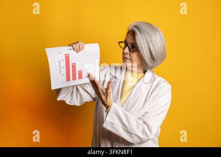 Senior woman scientist presenting financial bar chart showing decreasing sales Stock Photo