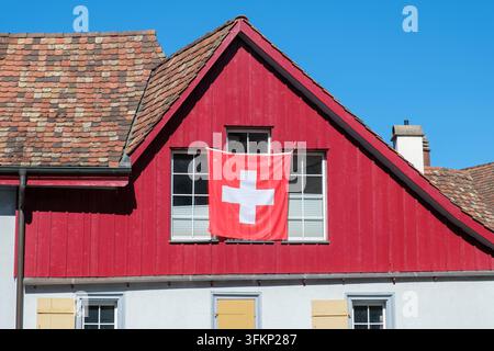 Traditional half-timbered building with red-painted gable and suspended national flag of Switzerland, Stein am Rhein, Canton of Schaffhausen, Switzerl Stock Photo