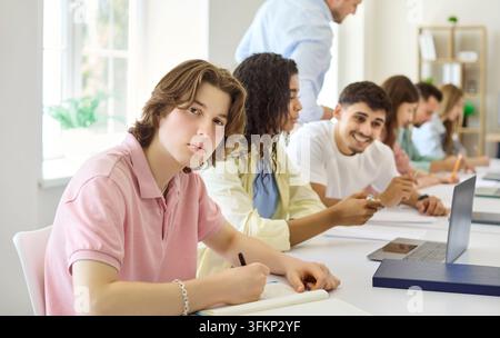 Diverse college students studying in classroom with laptops, notebooks and teacher Stock Photo