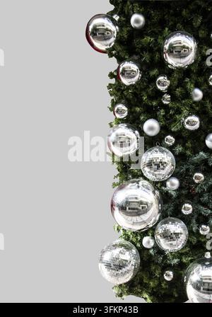 New Year and disco silver balls with glass elements, green Christmas tree branches isolated on grey background Stock Photo