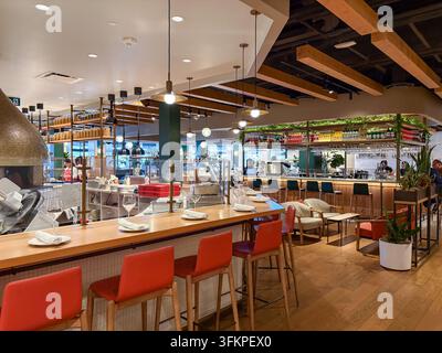 Modern restaurant interior featuring a stylish bar, contemporary seating, and an open kitchen with a pizza oven. Stock Photo