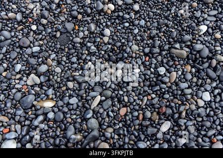 Wet black volcanic pebbles and smooth rounded stones create a dense natural texture at Reynisfjara Beach in South Iceland, seen from above. Stock Photo