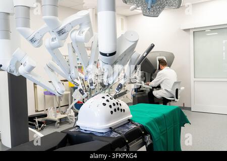 Doctor operating Da Vinci surgical robot console in hospital training room, medical robotics technology concept. Stock Photo
