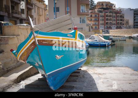 Moored traditional Maltese colourful wooden fishing boats in a small harbour off St Pauls Beach Bugibba Malta Stock Photo