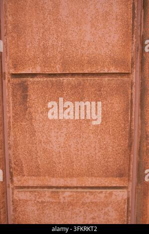 A vertical close-up shot focusing on structural metal sheets divided into geometric sections. The entire surface is coated in a thick, uniform layer o Stock Photo