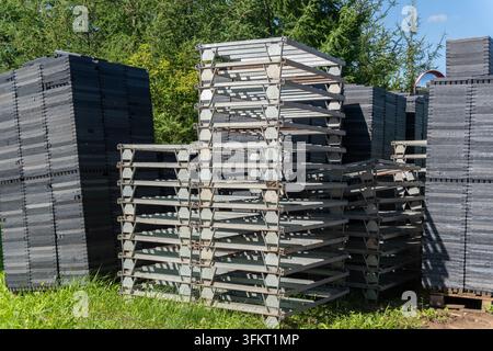 Stacks of black plastic crates and wooden pallets in agricultural farmyard Stock Photo