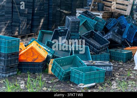 Heap of colorful plastic harvest crates piled outdoors on farm ground Stock Photo