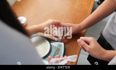 Students weighing chemical powder on a digital scale in a laboratory Stock Photo