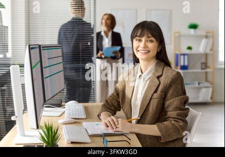 Businesswoman accountant in office using computer spreadsheet. She reviews a financial report, checks data accuracy and updates figures. Clear finance Stock Photo