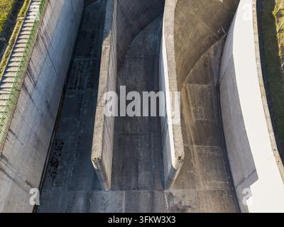 Aerial view of the concrete spillway structure of the Niedzica Dam on the Czorsztyn Reservoir, showcasing the geometric walls and textured surfaces in Stock Photo