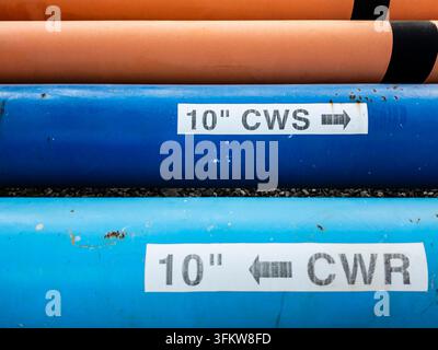 Close-up of pipe identification labels marking CWS (Cooling Water Supply) and CWR (Cooling Water Return) pipes at an industrial facility, showing stan Stock Photo