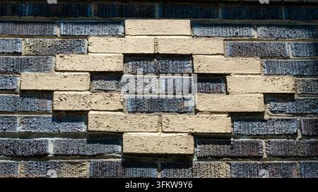The brick wall features a striking geometric pattern. Dark and light bricks create a bold contrast. Texture contrasts add depth and visual interest. P Stock Photo
