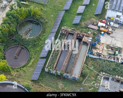 Aerial view of a wastewater treatment plant featuring circular sedimentation tanks and rows of solar panels in Krakow, Lesser Poland Voivode, Poland. Stock Photo