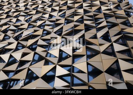 Modern building facade with golden triangular panels and reflective windows in Tirana, Albania Stock Photo