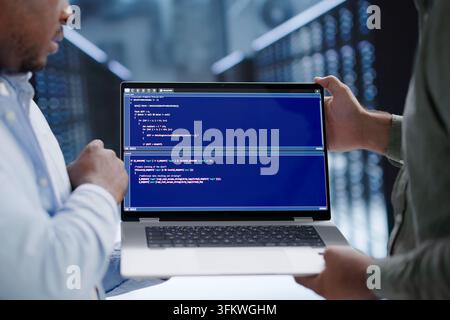 Programmer Reviews Code Security Details While Working In Busy Server Room. Stock Photo