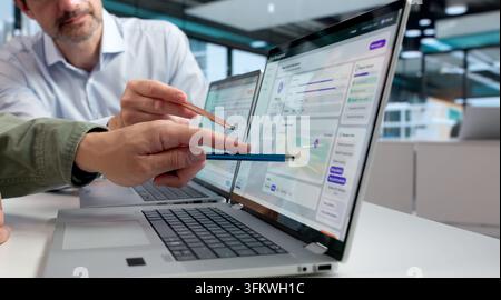 Human Resources Manager Reviews Employee Performance Data On Laptop During Meeting. Stock Photo