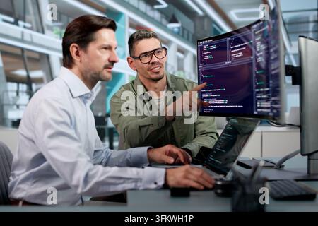 Software Engineer Carefully Reviews Code On Laptop To Build Secure Platform. Stock Photo