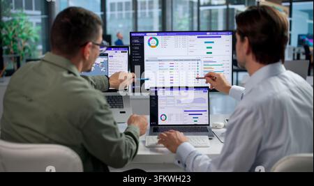 SEO Specialist Studying Website Traffic Graphs Closely With Colleague On Laptop. Stock Photo