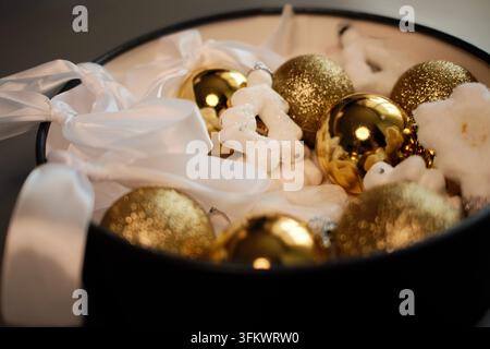 Golden Christmas baubles and white snowflake ornaments arranged inside a decorative bowl,creating a luxurious festive centerpiece for holiday interior Stock Photo