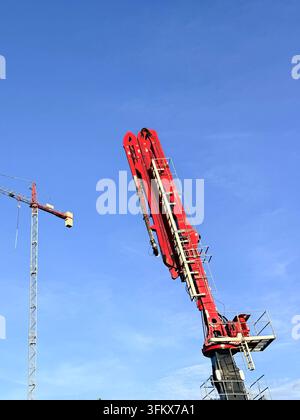 Tower cranes at a construction site against a clear blue sky. Industrial development and machinery concept. Stock Photo
