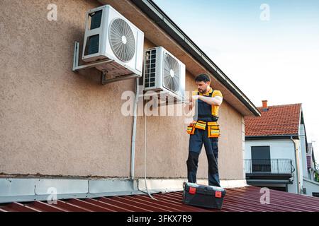 Repairman checking and fixing an hvac system on a building roof Stock Photo