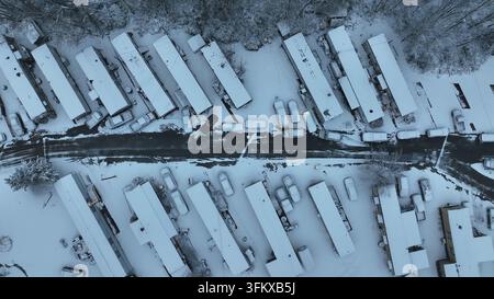 Aerial view of a mobile home park covered in fresh snow with rows of houses and parked cars along a narrow road in Forest, Virginia, United States. Stock Photo