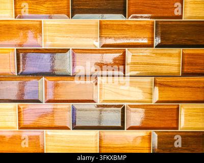 Ceramic or porcelain tiles with a wood pattern design in various shades of brown, orange, and yellow with a glossy and reflective surface. Stock Photo