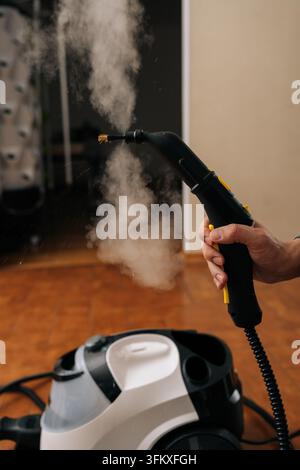 Person operating using steam cleaning machine, releasing powerful hot vapor for effective sanitation and deep cleaning purposes, ensuring hygiene and Stock Photo