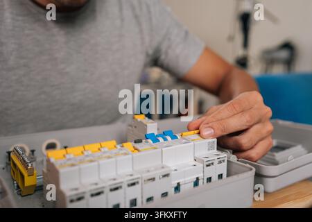 Close-up hands of unrecognizable person electrician connecting new circuit breaker inside electrical panel, ensuring safety and functionality of home Stock Photo