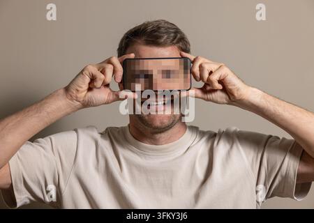 Anonymous identity and digital privacy concept with face hidden by phone Stock Photo