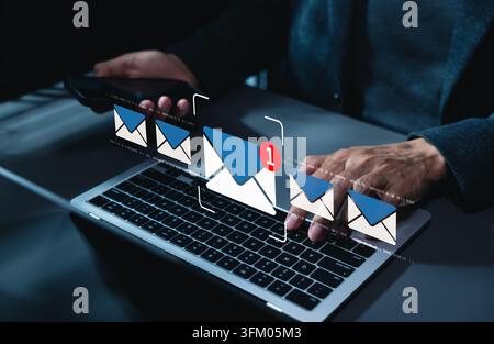 New email notification interaction concept. Person typing on laptop and using smartphone with digital interface showing new email notification symbol, Stock Photo