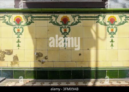 Vintage decorative ceramic wall tiles with repeating red floral motifs and green ornamental scrollwork on a historic shophouse in George Town, Penang, Stock Photo