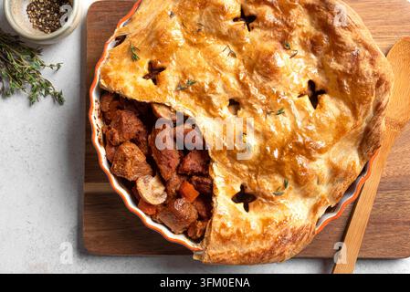 Beef steak and mushroom pie with puff pastry crust, top view, detailed. Homemade hearty family meat pie, comfort food. Stock Photo
