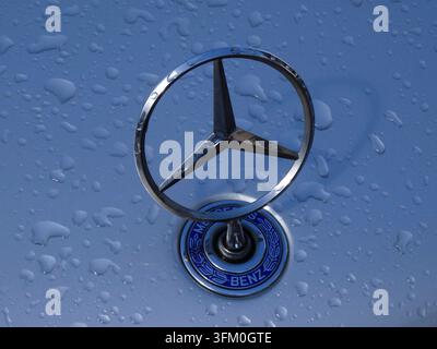 Mercedes-Benz hood ornament glistening with fresh raindrops on a blue car surface Stock Photo