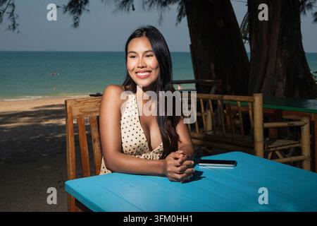 Young woman relaxing at outdoor seaside cafe with ocean view Stock Photo