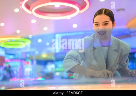 A medium shot taken from across the table of a happy young Southeast Asian Thai businesswoman from the Isan region smiling warmly at the camera while Stock Photo