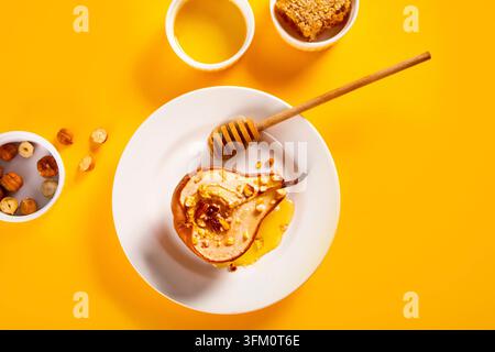 Honey or marple syrup roast pears with walnuts on a yellow background. Vegetarian nutrition health delicious dessert. View above Stock Photo