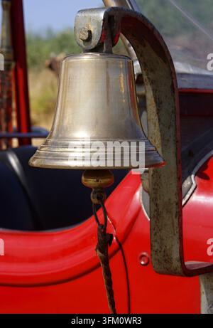 Shiny brass bell mounted on a classic red fire engine Stock Photo
