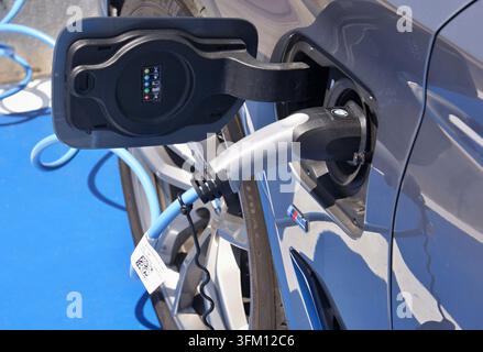 Electric car charging with blue cable and connector, showing sustainable energy concept Stock Photo